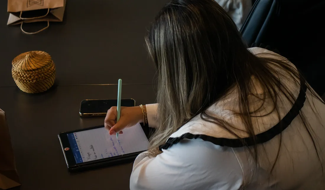 Profissional fazendo anotações em um tablet sobre a mesa